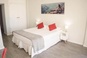 um quarto com uma grande cama branca com almofadas vermelhas em CLH Suites Domingos Ferreira no Rio de Janeiro