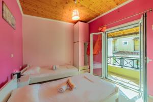 2 letti in una camera con pareti rosa e finestra di Elisavet Apts a Kávos