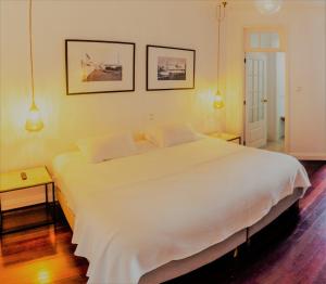 a large white bed in a bedroom with two pictures on the wall at Comercial Azores Boutique in Ponta Delgada