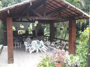 a patio with white chairs and a wooden pergola at Rancho Manacá in Guaramiranga +6 photos
