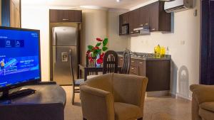 a living room with a television and a kitchen at Gran Hotel CCP Suites in Maturín