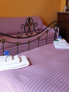 Una cama morada con toallas encima. en A Casa di Mamma, en Nápoles