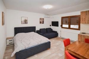 a bedroom with a bed and a couch and a table at Apartmani Vesto in Banja Luka