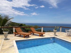 a patio with two chairs and a swimming pool at Casa das Ilhas in Ilhabela