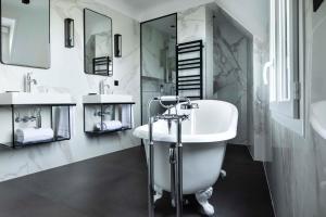 a white bathroom with two sinks and a tub at Maison 46 in Paris