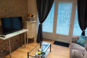 een woonkamer met een tv en een raam bij Au Mont Pour Deux in Pontorson