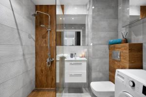 a bathroom with a shower and a toilet and a sink at Elite Apartments Marine Suite in Gdańsk