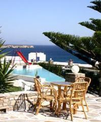 a patio with a table and chairs and a pool at Silver Rocks Hotel in Chrissi Akti