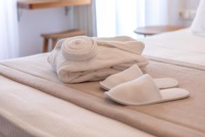ナクソス・コラにあるCastle Mansionsのベッドの上にタオルとスリッパを用意しています。