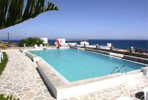 a large blue swimming pool next to the ocean at Silver Rocks Hotel in Chrissi Akti