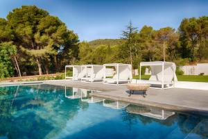 una piscina con sillas blancas, una mesa y agua en Hotel Eetu - Adults Only, en Begur