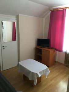 ヴィスワにあるAgusiaのテーブル、テレビ、ピンクのカーテンが備わる客室です。