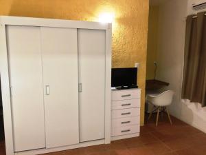 um armário branco com uma televisão e uma cadeira branca em Hotel Colonial em Maldonado