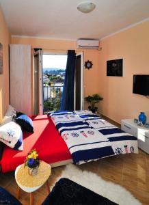 Schlafzimmer mit einem roten und blauen Bett und einem Fenster in der Unterkunft Apartments M&T in Tivat