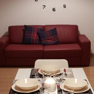 a living room with a red couch and a table with dishes at Sweet Home in Falconara Marittima