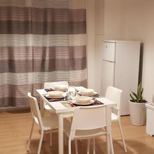 a white table with white chairs and a white refrigerator at Sweet Home in Falconara Marittima