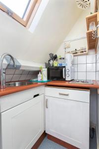 una cocina con armarios blancos y fregadero en Residentie Blijdorp, en Róterdam