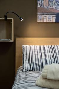 a bed with a striped pillow and a lamp at Dimora delle Sciare - Centro Storico in Catania