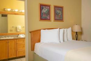 a bedroom with a bed and a sink and a mirror at Raintree's Cimarron Golf Resort Palm Springs in Cathedral City