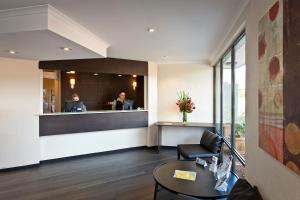 een lobby met een receptie en een vrouw in een kantoor bij ibis Styles Canberra Tall Trees in Canberra
