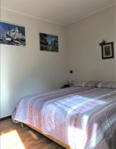 a bedroom with a bed and two pictures on the wall at Condominio Ginepro in Carisolo
