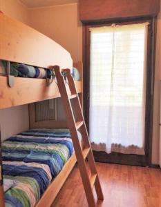 Łóżko piętrowe w pokoju z drabiną obok okna w obiekcie Condominio Ginepro w mieście Carisolo