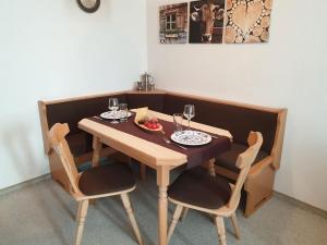 una mesa de madera con 2 sillas y copas de vino. en Haus Andrea, en Fischen