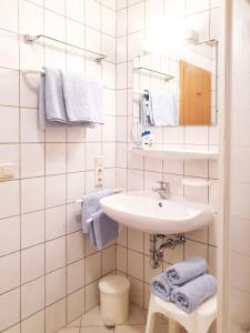 a white bathroom with a sink and blue towels at Haus Andrea in Fischen