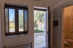 a bathroom with a window and a toilet and a door at Relais La Masseriola in Castellana Grotte