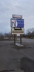a large sign in a parking lot next to a street at Niagara Inn in Niagara Falls