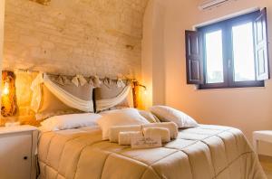 a bedroom with a bed with white sheets and a window at Relais La Masseriola in Castellana Grotte