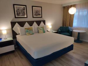 a bedroom with a large white bed and a blue chair at Kings Inn in San Diego