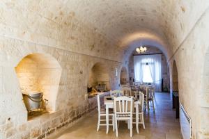 a dining room with tables and chairs in a stone wall at Relais La Masseriola in Castellana Grotte