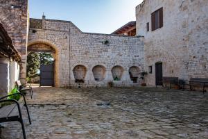 un antiguo edificio de piedra con un patio de piedra con bancos en Relais La Masseriola en Castellana Grotte