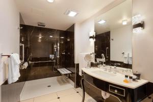 a bathroom with a sink, mirror, and bathtub at Hotel Retlaw, Trademark Collection by Wyndham in Fond du Lac