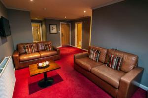 a living room with two leather couches and a table at The Gibside Hotel in Gateshead