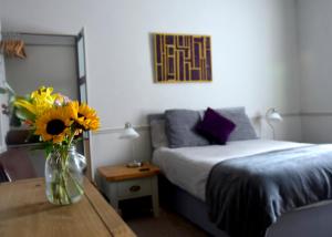 1 dormitorio con 1 cama y un jarrón de flores sobre una mesa en Westham en Warwick