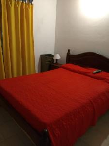 1 dormitorio con cama roja y cortina amarilla en Complejo Lucas Frente al Mar en Mar de Ajó