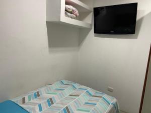 a bedroom with a bed and a tv on the wall at STUDIO DELFINES / BOCAGRANDE in Cartagena de Indias