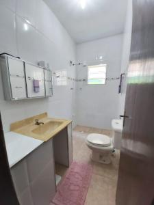 a white bathroom with a toilet and a sink at Maranata Casa com Piscina - 2 minutos de carro até o mar in Peruíbe