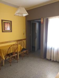 Habitación con mesa, sillas y pared amarilla. en Un apartamento céntrico en Mar del Plata en Mar del Plata