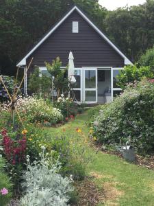 a house with a garden with flowers in the yard at Hahei Kereru Cottage in Hahei