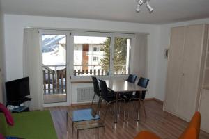 a living room with a table and chairs and a large window at Mireille, Appartment 61 in Leukerbad