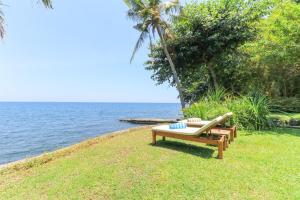 a bench sitting on the grass next to the ocean at Palm Beach Villas Bali in Singaraja
