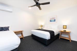 a bedroom with two beds and a ceiling fan at Hotel Forster in Forster