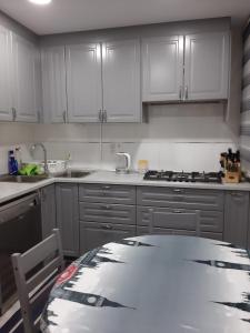 kuchnia z białymi szafkami i stołem w obiekcie Nur Apartment w mieście Terrassa
