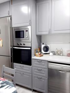 kuchnia z urządzeniami ze stali nierdzewnej i białymi szafkami w obiekcie Nur Apartment w mieście Terrassa