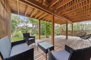a wooden deck with chairs and tables and a wooden pergola at Chic Beach Studio in Rye