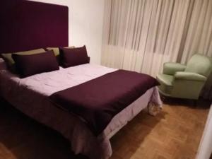 1 dormitorio con 1 cama y 1 silla verde en Casa Ripozi M Moreno en Córdoba
