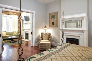 a bedroom with a bed and a chair and a fireplace at Newly Renovated Historic Savannah Townhome! in Savannah